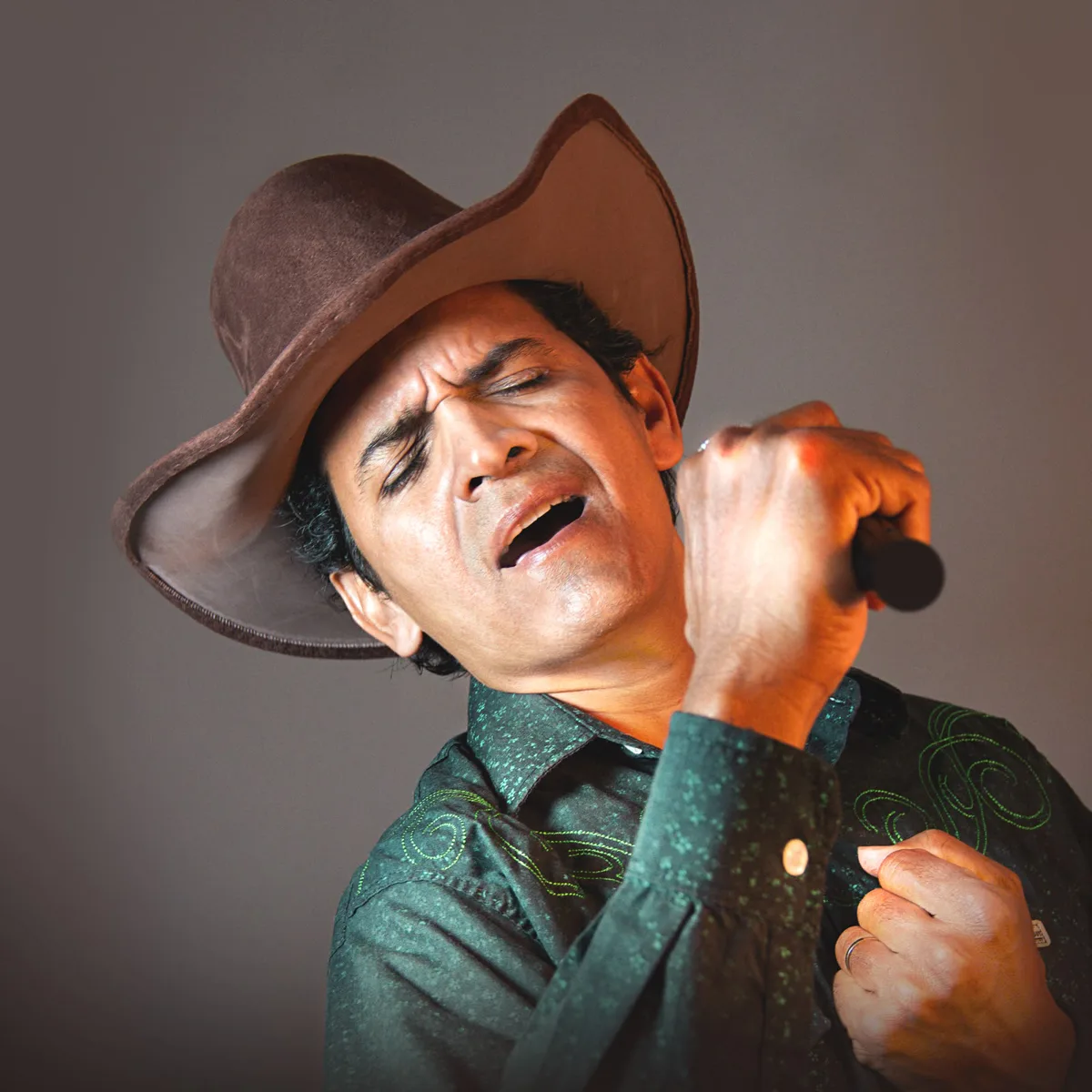 Naldin Trupela cantando com a camisa verde bordada